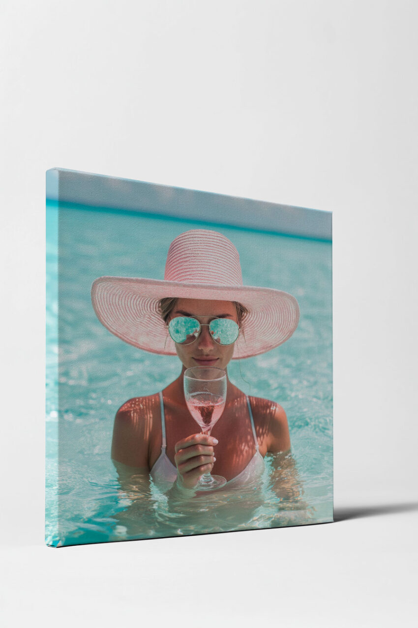 Poster einer Frau mit großem rosa Sonnenhut im Wasser, die ein Glas Rosé hält, sommerlicher Stil mit Blau und Rosa